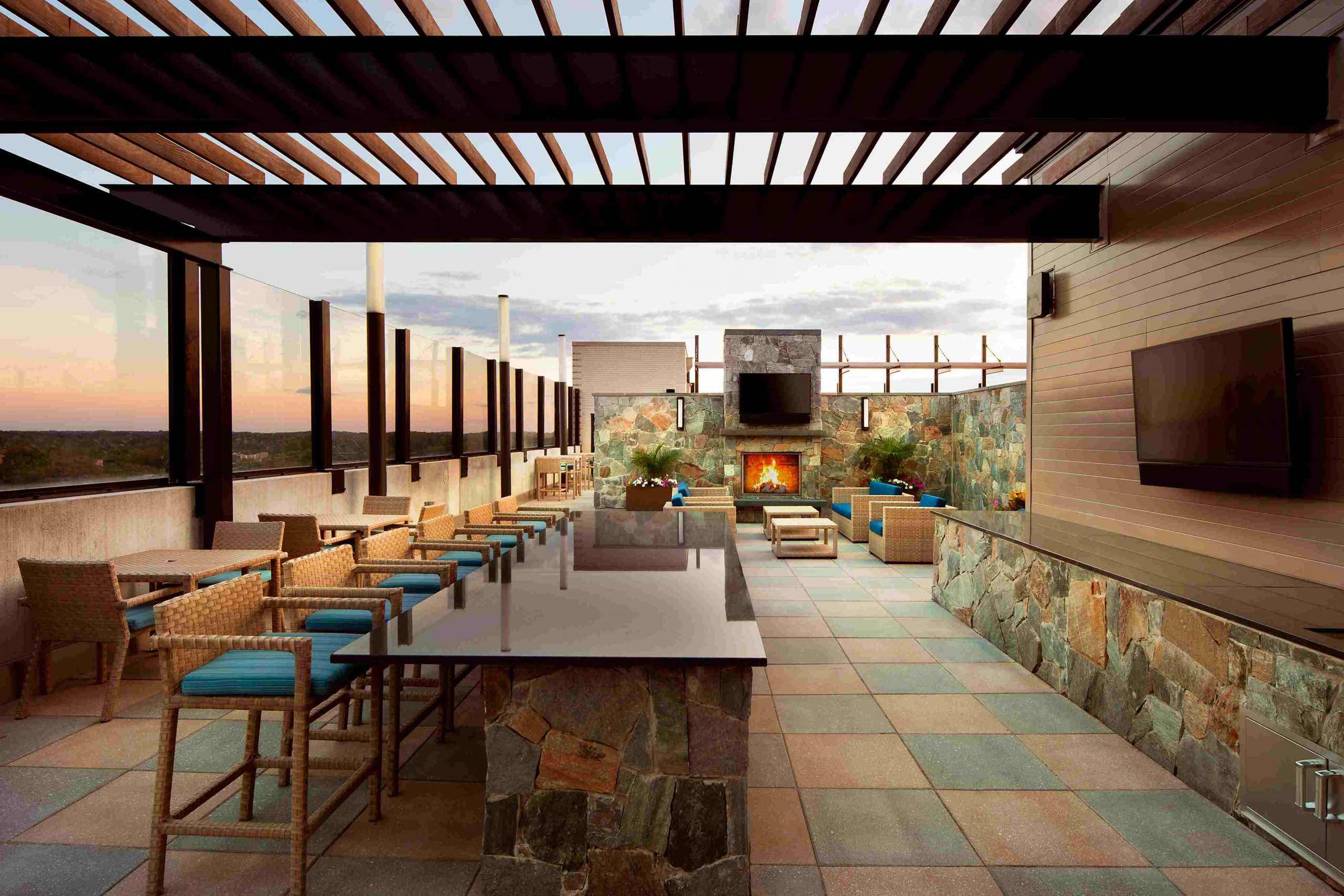 Faraday Park rooftop featuring a bar, tables, lounge chairs, multiple televisions, and fireplace